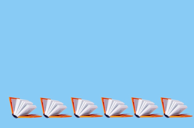 Books in orange covers on a blue background copy space