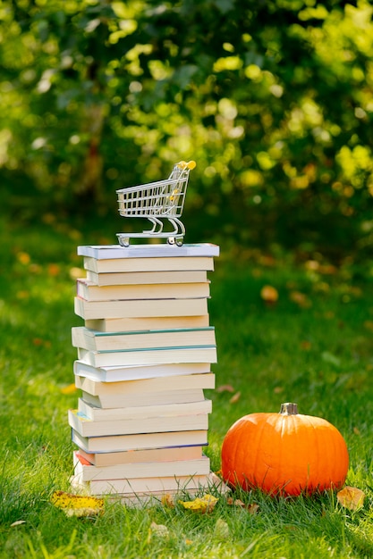 Libri e zucca con carrello su erba verde in un giardino