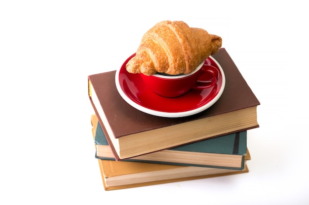 Books and red cup of coffee with  croissant on white background