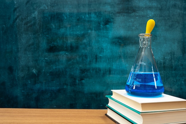 Photo books and scientific experiment tools on the desk. empty blackboard. education concept.