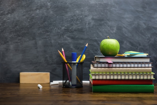 Books, stationery and education supplies on wooden desk in classroom 