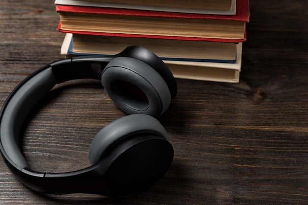 Books and stereo headphones. Listen to music and read. Wooden background, closeup