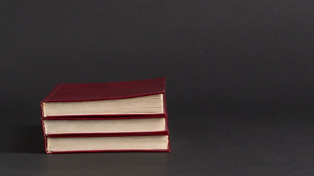 Books with red cover on black background, isolated. back to school