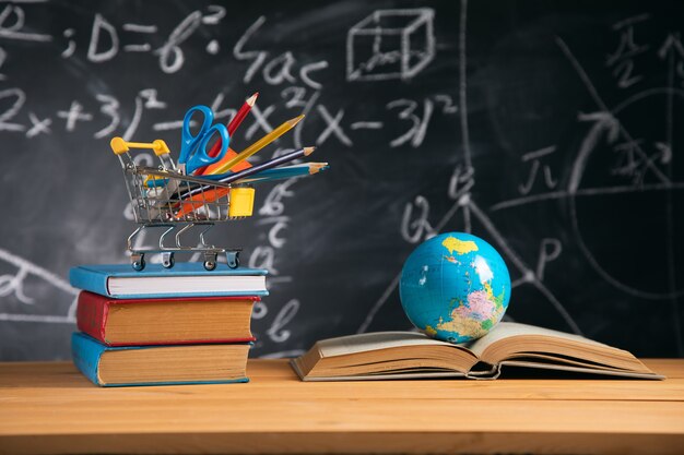 Books with stationary and globe on board background