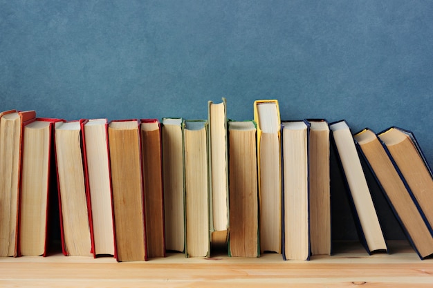 Books on the wooden shelf on a blue background.