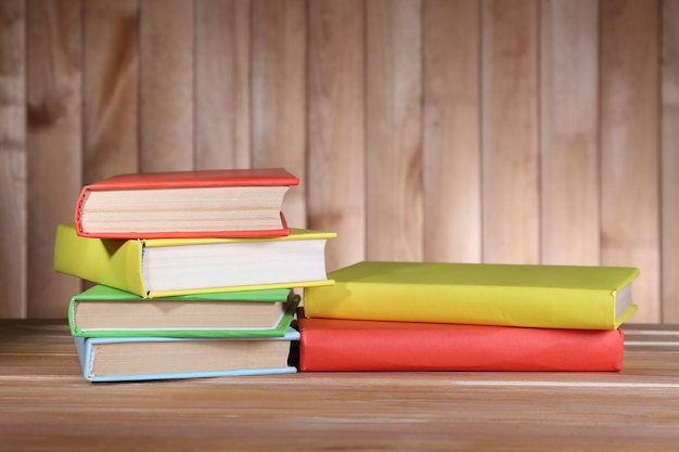 Books on wooden table on wooden wall background