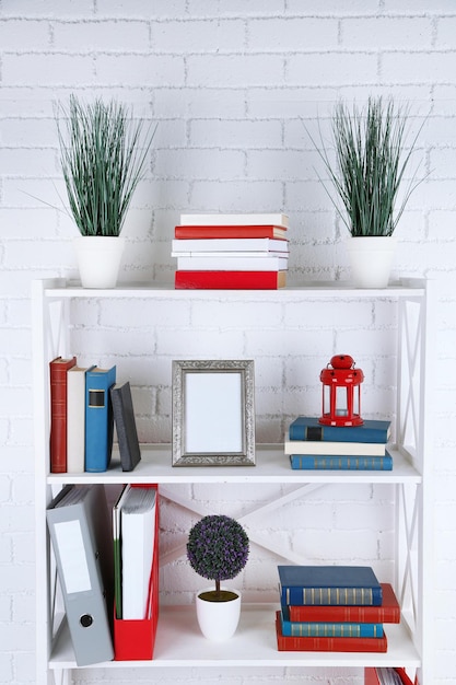 Bookshelves with books and decorative objects on brick wall background