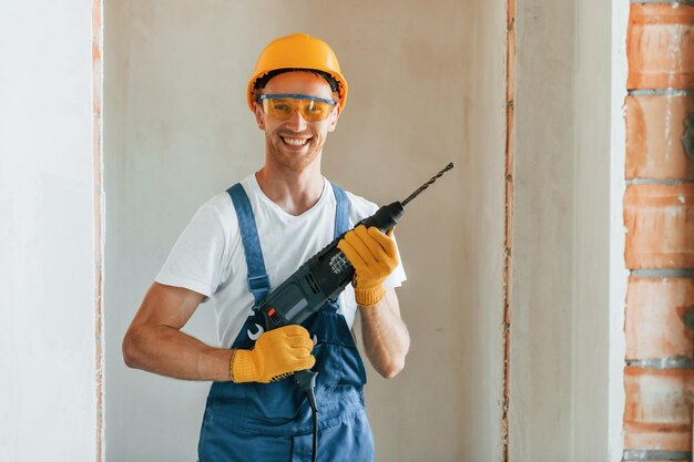 Boor houden Jonge man aan het werk in uniform in de bouw overdag