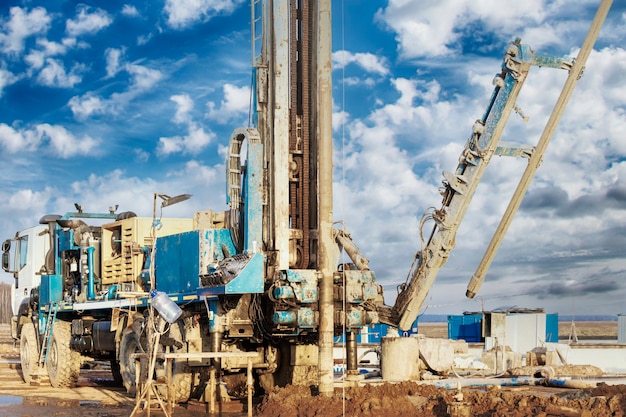 Boorinstallatie in een veld onder een blauwe bewolkte hemel. Het boren van diepe putten. Geologische verkenning. Minerale exploratie.