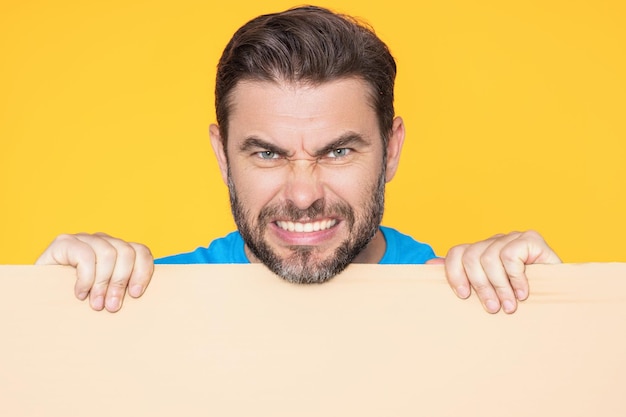 Boos close-up gezicht van de mens met lege banneradvertentie poseren geïsoleerd over studio achtergrond portret van een