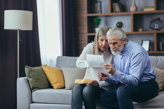 Boos gefrustreerd document senior koppel Ongelukkig oud gezin dat gestrest raakt Ernstige oudere echtgenoot die bankpapieren documentrekeningen belastingen laat zien aan verwarde oudere vrouw in huis Bezorgd uitziend hulpprogramma