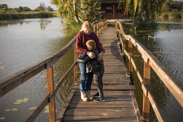 Boos jonge moeder geeft troostende knuffel aan huilend zoontje Knappe jongen ziet er verdrietig uit en kleine jongen moet bij mama blijven omdat zijn vader en moeder gescheiden zijn of scheiden