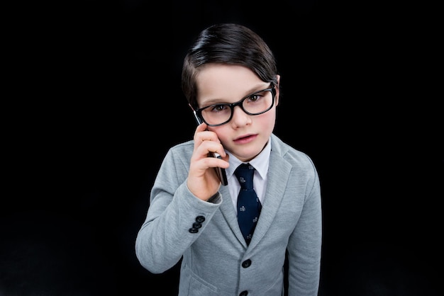 Boos jongen met behulp van smartphone geïsoleerd op zwart