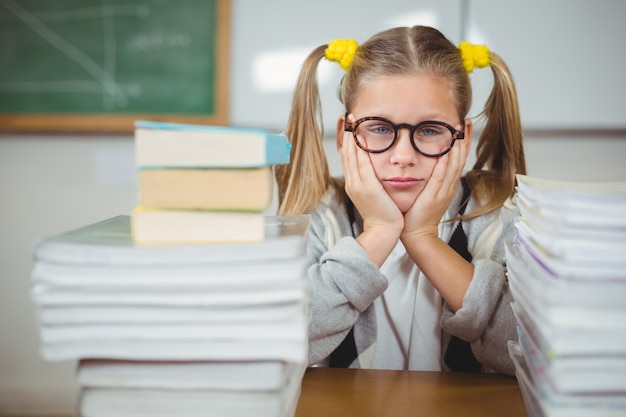 Boos leerling tussen stapel boeken op haar bureau