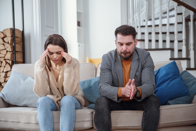 Boos man aan tafel en vrouw met boodschappentassen op kamer. Geldproblemen in relatie