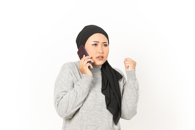 Boos op de telefoon van mooie Aziatische vrouw die hijab draagt die op witte achtergrond wordt geïsoleerd