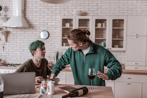 Foto boos op vrouw. blondharige man met groen shirt boos op vrouw die alleen alcohol drinkt