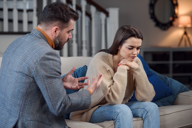 Boos paar met argument of verbreken. Jonge man en vrouw hebben ruzie terwijl zittend op een bank in de woonkamer in een groot huis. Ontrouw concept.