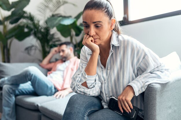 Boos paar samen op de bank zitten en thuis naar tegenovergestelde kanten kijken