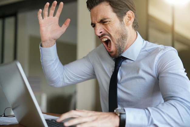 Boos zakenman die geduld verliezen en bij laptop in modern bureau gillen