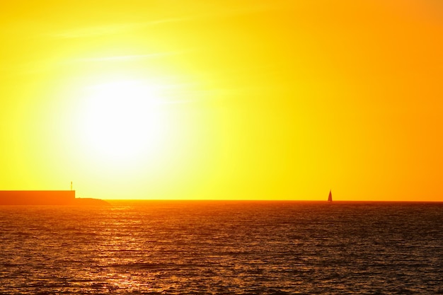 Boot in de zee van Alghero onder een felle zon bij zonsondergang