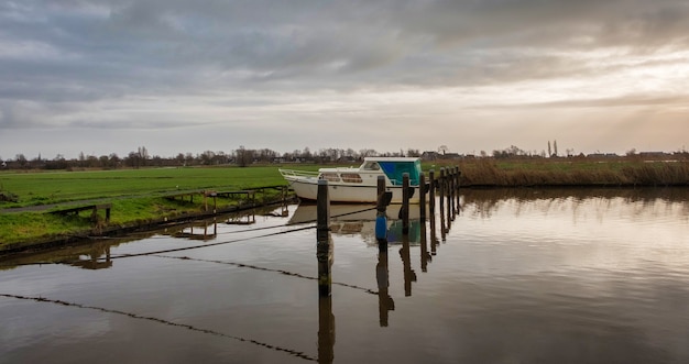 Boot in haven tegen Nederlandse bewolkte hemel in de herfst in Nederland