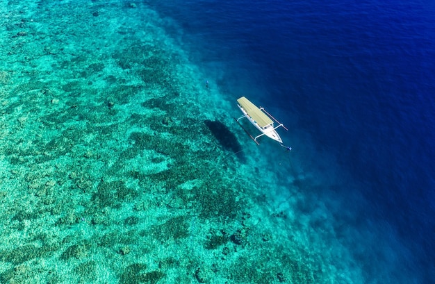 Boot op het wateroppervlak van bovenaanzicht Turquoise waterachtergrond van bovenaanzicht Zomerzeegezicht vanuit de lucht Gili Meno-eiland Indonesië Reisbeeld