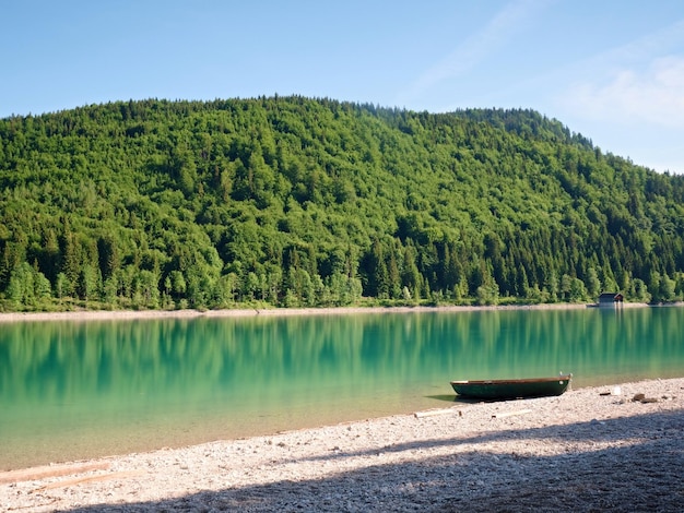 Foto boot verankerd aan de oever van de alpen meer bergen weerspiegeld in het gladde waterniveau van het blauwe meer