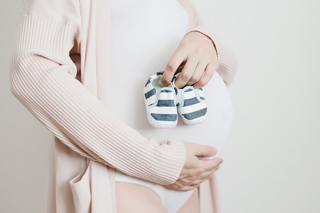 booties in the hands of a future mother with pregnant belly