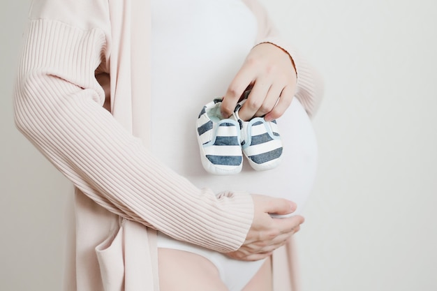 Booties in the hands of a future mother with pregnant belly