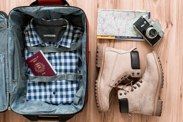 Boots and camera near opened suitcase