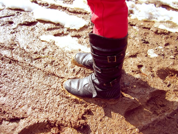 春の道路の泥の中のブーツ
