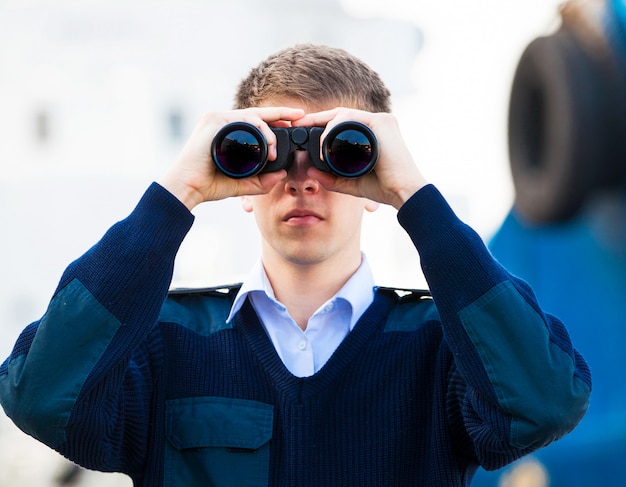 Bootsman met een verrekijker in de buurt van de boot.