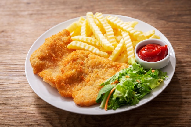 Bord gebakken gepaneerd kippenvlees of Schnitzel met patat en salade