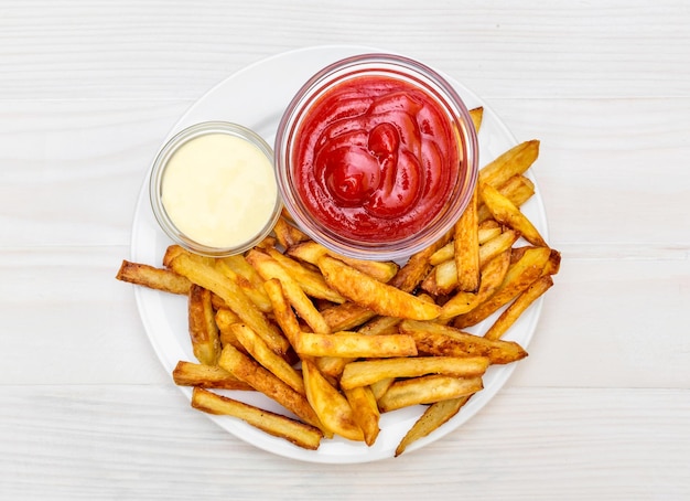 Bord met friet, aardappelketchup en mayonaise op tafel Bovenaanzicht