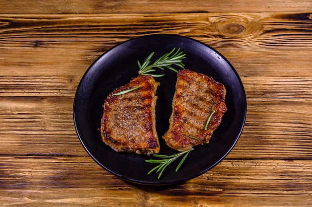 Bord met geroosterde steaks en rozemarijntakjes op een houten tafel