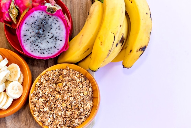 Bord met gesneden bananen, muesli en pitaya in tweeën gesneden. Bovenaanzicht.