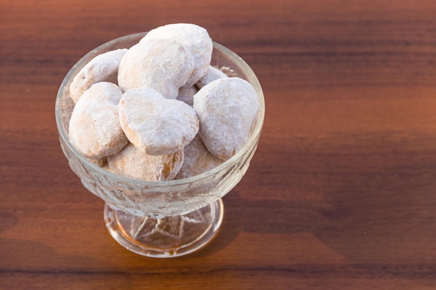 Bord met hartvormige koekjes bedekt met poedersuiker op houten tafel