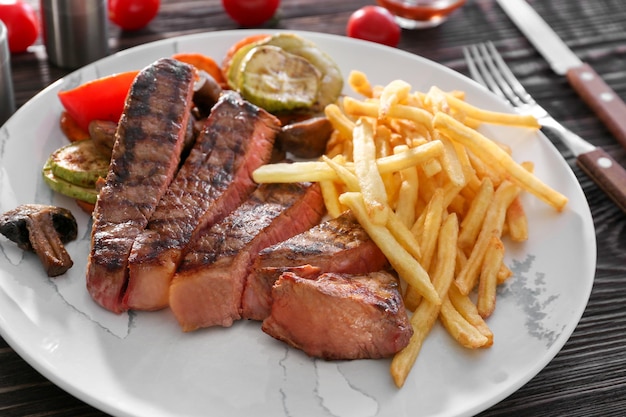 Bord met heerlijke gegrilde biefstuk en frietjes op houten tafel