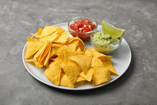 Bord met heerlijke Mexicaanse nacho's, chips en sauzen op grijze tafel