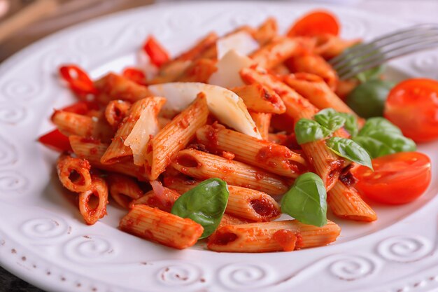 Bord met heerlijke penne pasta en garnituur, close-up