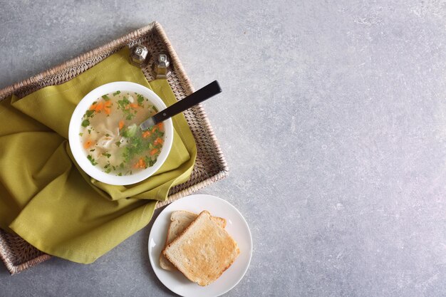 Bord met huisgemaakte kippensoep op rieten dienblad