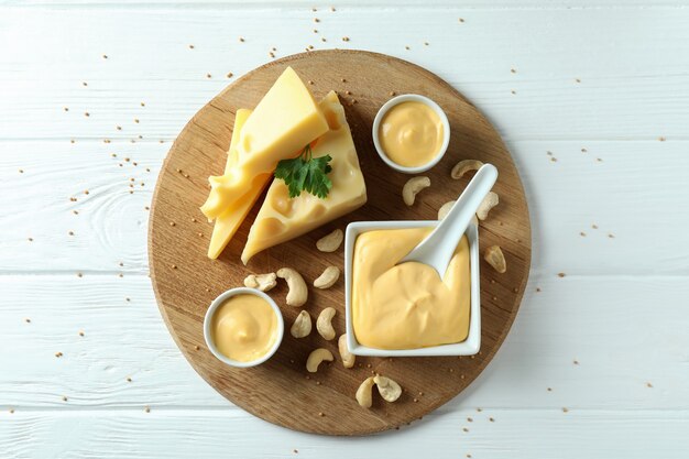 Bord met kaassaus en ingrediënten op witte houten tafel