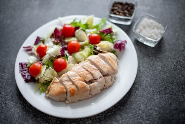 Bord met kipfilet en salade met groenten op een stenen ondergrond