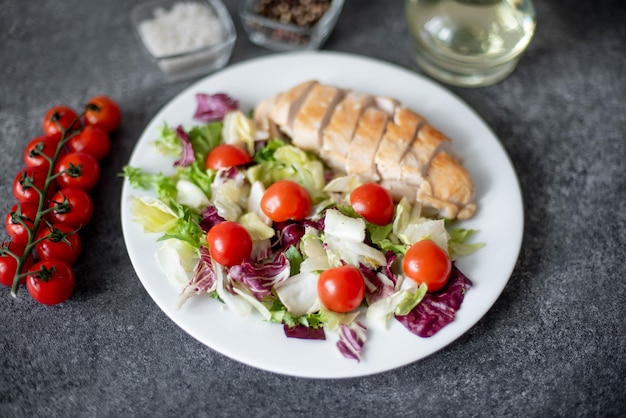 bord met kipfilet en salade met groenten op een stenen ondergrond