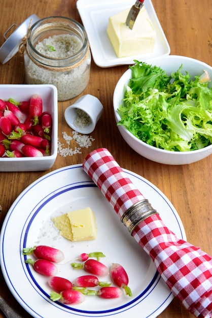 Bord met radijs, boter en salade op een rustieke tafel