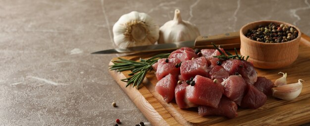 Bord met rauw vlees, kruiden en specerijen op grijze tafel