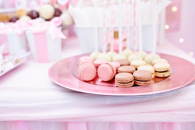 Bord met smakelijke bitterkoekjes en cakepops voor het zoete feest Candy bar, pastelroze en crèmekleurig