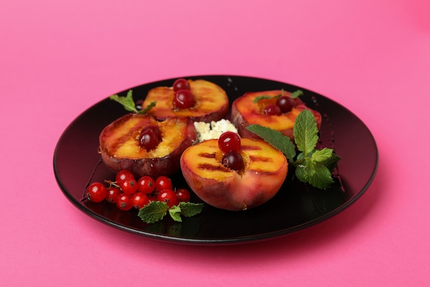 Bord met smakelijke gegrilde perzik op roze achtergrond