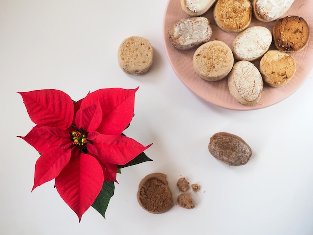 Bord met Spaanse kerstkoekjes Estepa Polvoron Mantecado Nevaditos en Poinsettia op wit